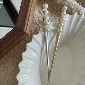 Épingles à cheveux dorées et argentées avec perles verticales sur une coupelle en céramique