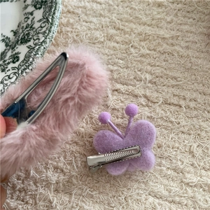 Détail de la barrette en peluche rose et du clip papillon en feutre violet sur céramique