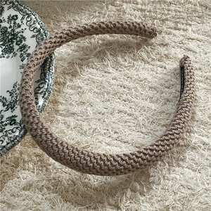 Detail of a brown knitted sponge headband showing soft texture and handmade label