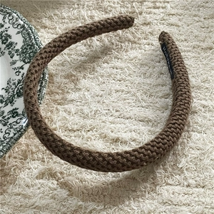 Close-up of brown knitted headband showing spiral texture and Hand Made label detail