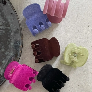 Vista dettagliata di 6 mollette per capelli colorate floccate su fondo grigio