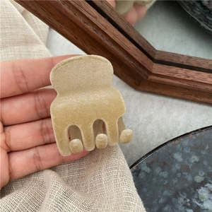 Dettaglio di un fermaglio per capelli floccato beige tenuto a mano in un set accogliente