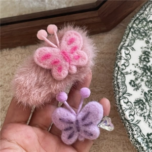 Détail de pinces à cheveux papillon en peluche rose et violette avec de jolies broderies