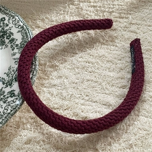 Close-up of wine red knitted headband with handmade label on a soft plush background