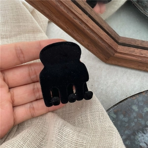 Dettaglio di una piccola molletta per capelli nera floccata con finitura opaca morbida