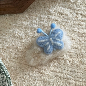 Détail d'une pince à cheveux papillon en peluche bleue sur base en fausse fourrure