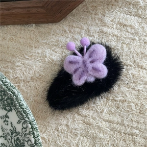 Vue détaillée d'une barrette papillon en peluche violette avec base en velours noir