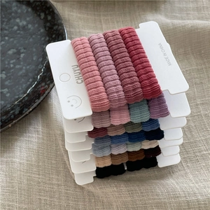 Détail d'élastiques à cheveux colorés sur emballage carton sur fond en lin doux