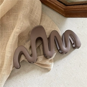 Gros plan d'une pince à cheveux mate marron sur tissu beige et surface en pierre