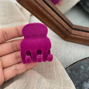 Dettaglio della mini clip per capelli viola scuro con una morbida texture opaca in velluto