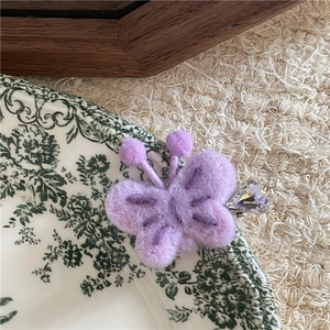 Détail d'une barrette papillon en feutre violet avec broderie et cristal en forme de cœur