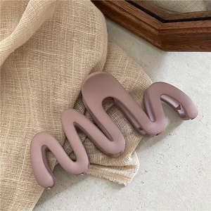 Détail de la pince à cheveux ondulée rose mat avec texture givrée sur lin beige