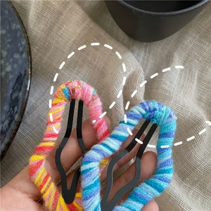 Detailed close-up of colorful wool knitted hollow cloud hair clips in vibrant hand-held view