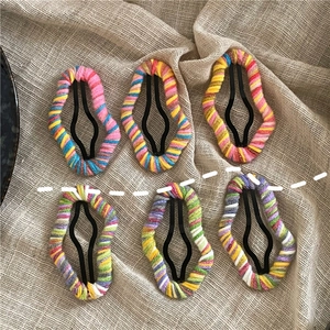 Detailed view of six colorful yarn wrapped cloud shaped BB hair clips on linen fabric