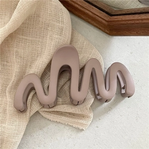 Détail d'une pince à cheveux mate de 13 cm rose poudré sur fond minimaliste en lin tissé