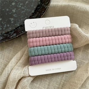 Détail de quatre chouchous en velours côtelé doux aux couleurs pastel sur carte
