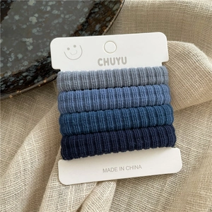 Détail de quatre chouchous élastiques bleus dégradés sur une carte en forme de cœur