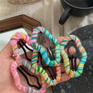 Close-up of four colorful handmade yarn-wrapped cloud hair clips held in hand