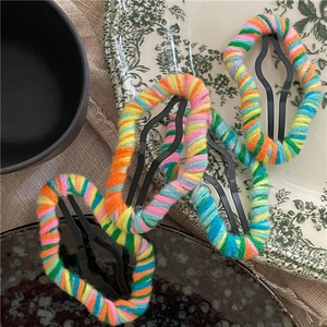 Set of four colorful yarn-wrapped cloud hair clips shown on a rustic fabric background