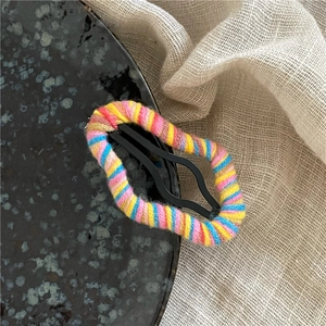 Detailed macro view of colorful wool yarn wrapped BB hair clip with vibrant stripes