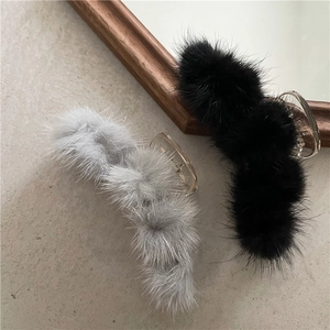 Detail showing soft black and grey plush hair claws with fur pom poms on a textured surface