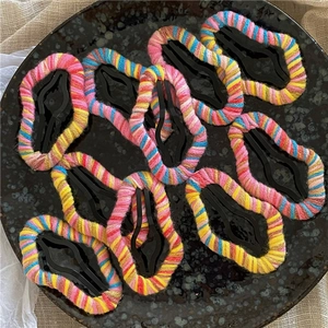 Close-up of colorful yarn-wrapped BB hair clips in a teardrop shape on a tray