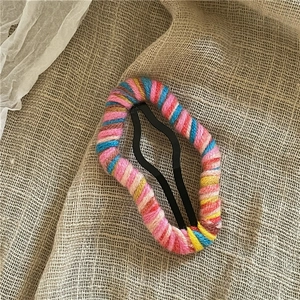 Detailed macro view of multi-colored yarn wrapped cloud hair clip on rustic linen fabric