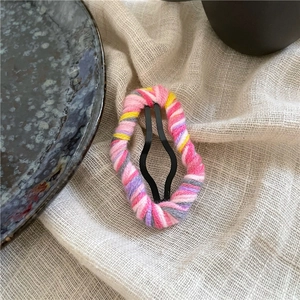 Detailed close-up of colorful wool yarn wrapped cloud hair clip with metal base
