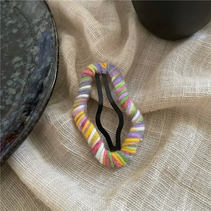 Detailed view of handmade colorful yarn-wrapped cloud BB hair clip on soft cotton fabric
