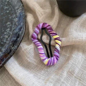 Detailed macro view of colorful knitted wool yarn texture on a cloud-style metal hair clip