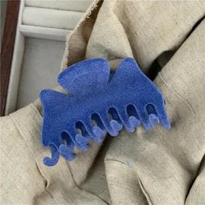 Detail of blue flocked claw clip showing plush texture on soft beige linen background