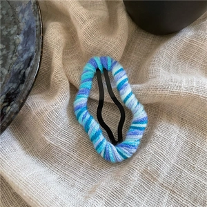 Close-up of handmade colorful yarn-wrapped water drop BB clip hair accessory on linen fabric