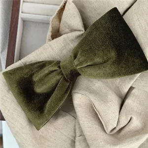 Detail of olive green velvet bow hair claw clip with rich texture on linen background