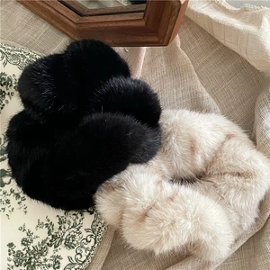 Close-up of oversized plush faux mink fur scrunchies in black and beige cream colors