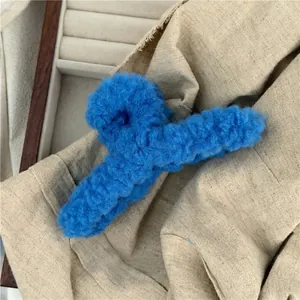 Close-up of fluffy blue plush hair claw clip with warm texture on wooden jewelry tray