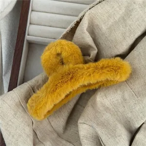 Close-up of ginger yellow plush hair claw clip with faux fur texture on white jewelry dish