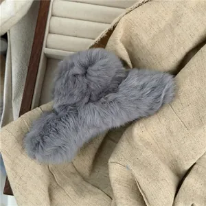 Close-up of a large grey plush faux fur hair claw clip on a beige linen background