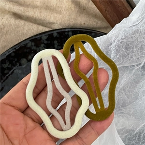 Close-up of wavy flocked hair clips in cream and olive green with soft matte texture