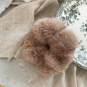 Detailed view of plush light brown faux mink fur scrunchie on a decorative plate
