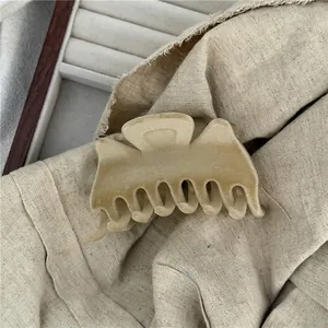 Detail of a soft beige plush hair claw clip on a textured linen fabric background
