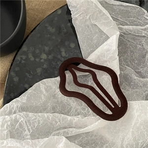 Close-up of a coffee brown flocked wave hair clip on a textured dark and white background