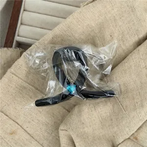 Glossy black hair claw clip featuring a blue crystal heart, shown in clear packaging