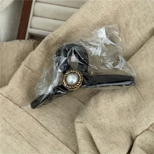 Macro shot of vintage black claw clip featuring a large faux pearl with gold twisted border