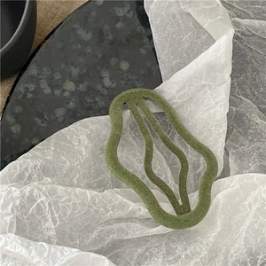 Detail of Morandi green flocked hair clip with irregular wavy hollow design on stone