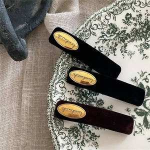 Detail of velvet BB hair clips with gold handmade oval labels on vintage porcelain plate