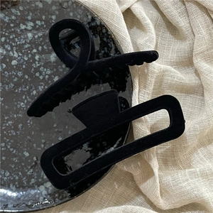 Close-up of black flocked geometric hair claws with matte texture on elegant fabric