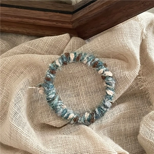 Détail de l'élastique en laine tissée bleu et marron sur fond de lin naturel