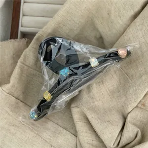 Detail of a black hair claw clip featuring five colorful geometric faux gemstones on fabric