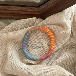 Détail d'élastiques à cheveux bohèmes tissés en spirale pourpre et sarcelle sur lin