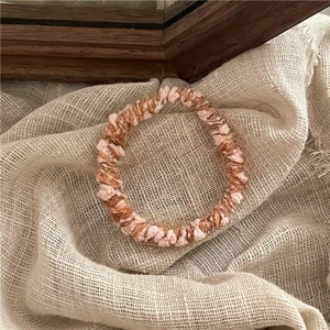 Vue détaillée de l'élastique à cheveux en tricot rose et marron sur tissu en lin beige
